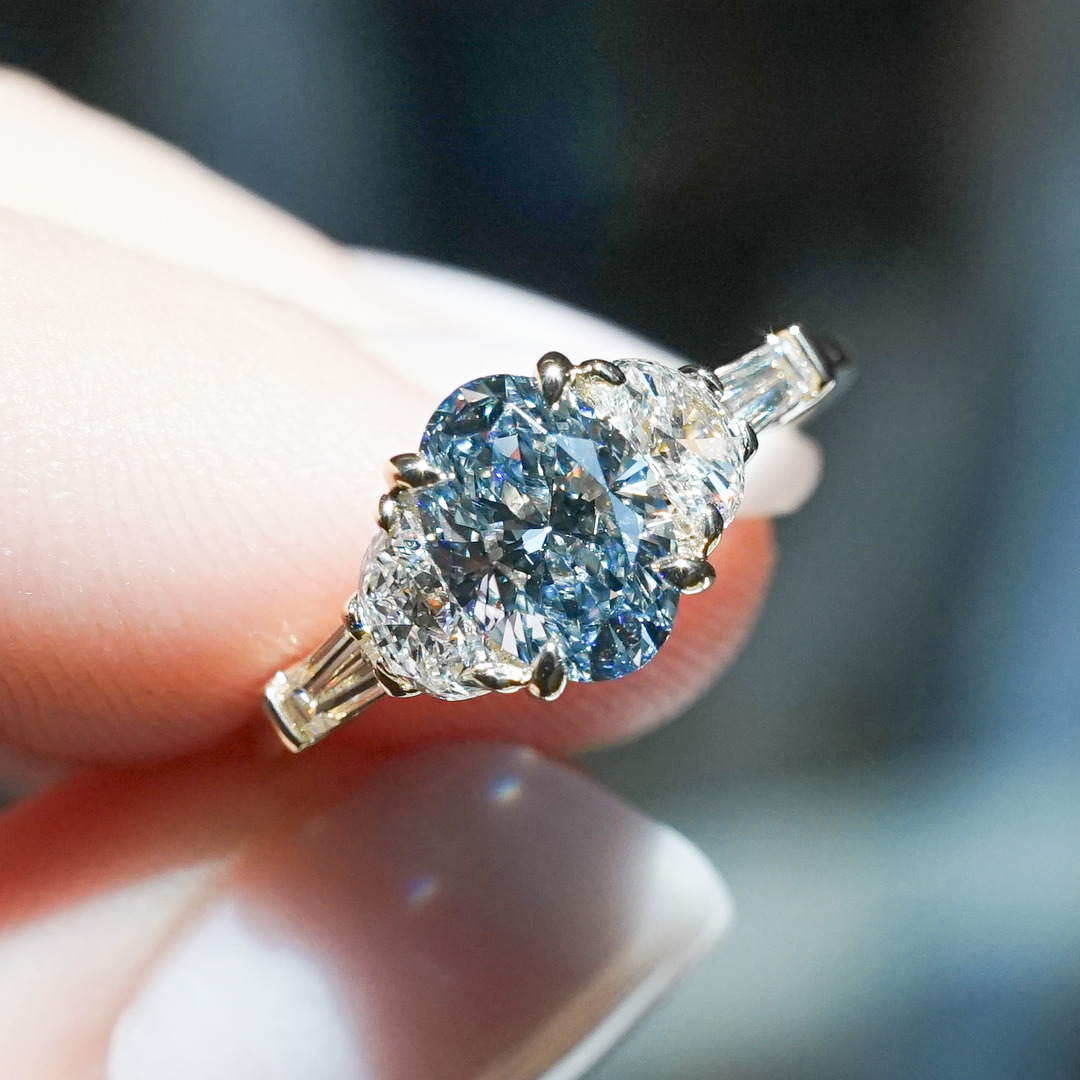 A five stone engagement ring with tapered baguettes and half moon side stones and fancy colored blue oval diamond set in platinum 