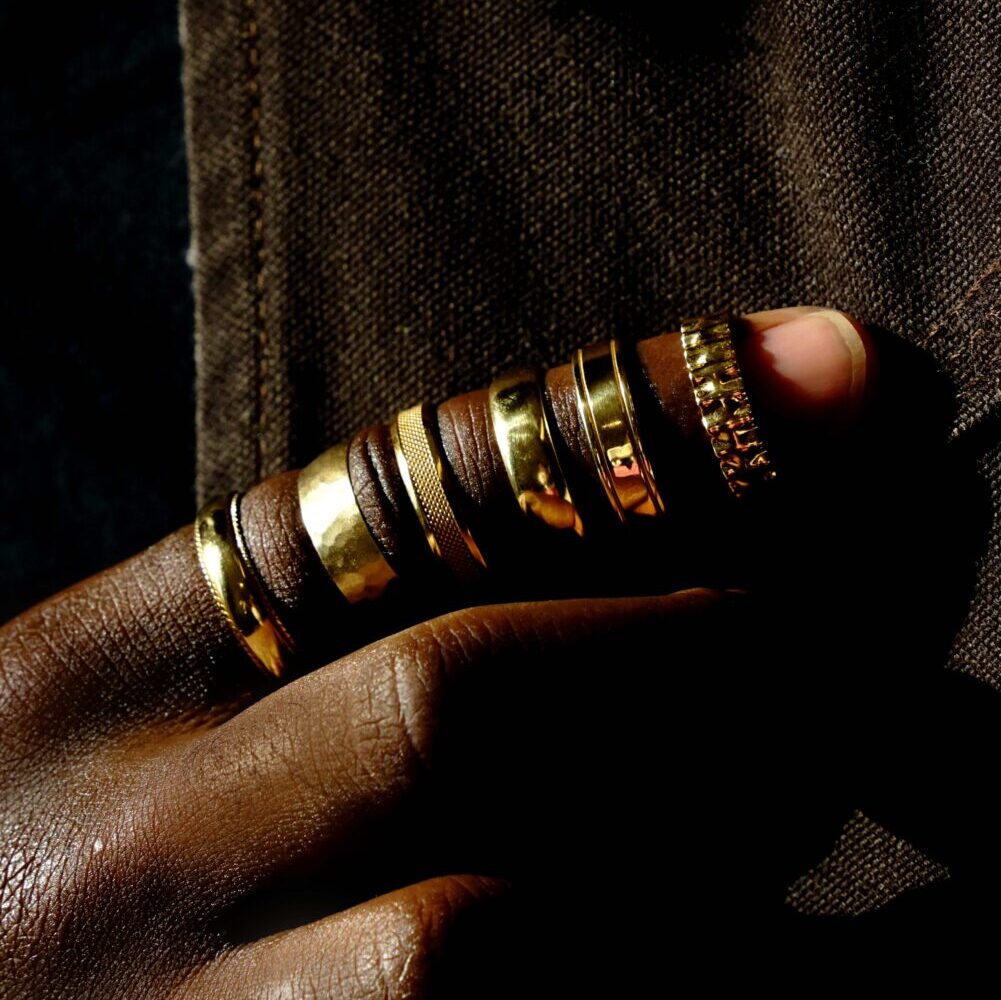 Six men's wedding bands in yellow gold, sit on a finger