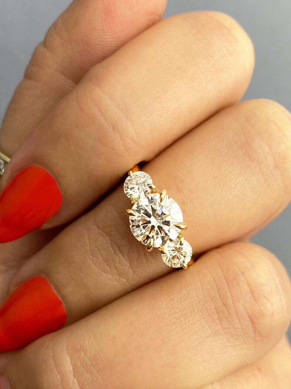 A round brilliant diamond three stone ring. A large round diamond is framed by two smaller round brilliants. 