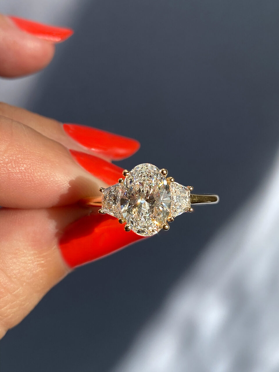 Oval diamond three stone ring with trapezoids