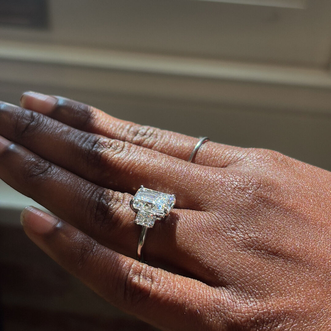 A woman wears a three stone radiant cut engagement ring in platinum 